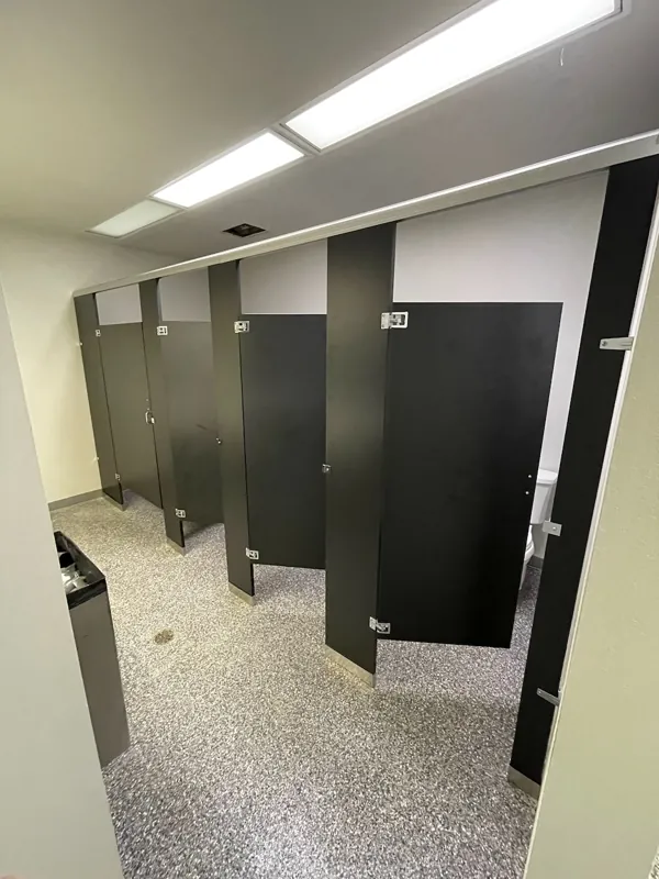 Black restroom compartments above a terrazzo floor