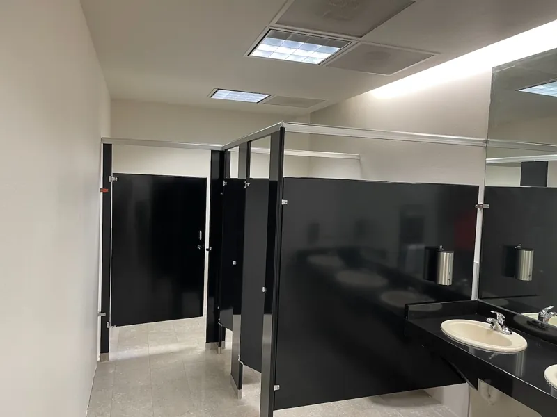 Black restroom partitions beside a stone counter