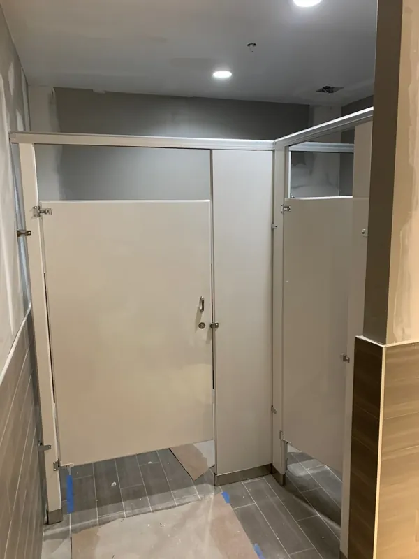 A compact gray restroom compartment in a tiled room