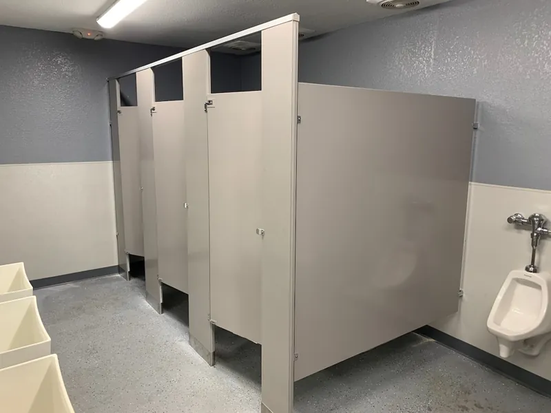 Gray toilet compartments and urinal privacy screens in a tiled restroom