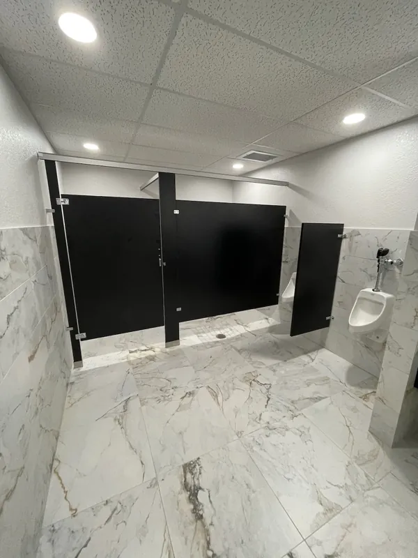 Dark restroom partitions against marble-look wall tile
