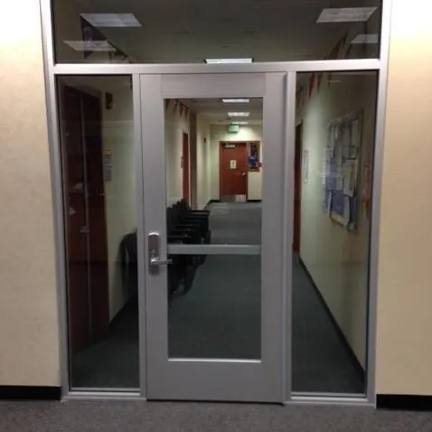 A gray door with a large glass panel leading into a corridor