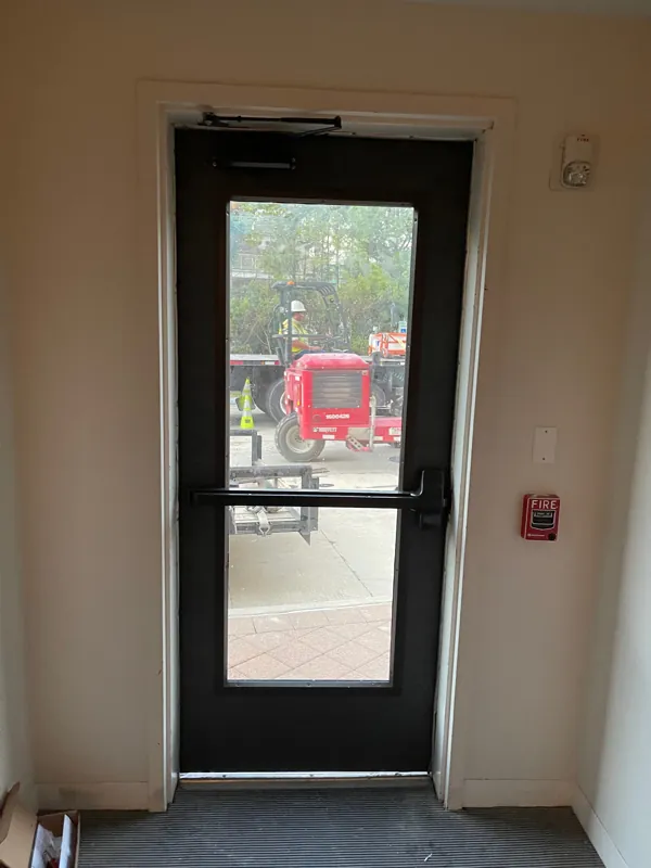 A dark glazed exit door fitted with an exit device