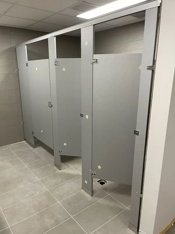 Gray restroom doors and dividing panels in a light tiled room