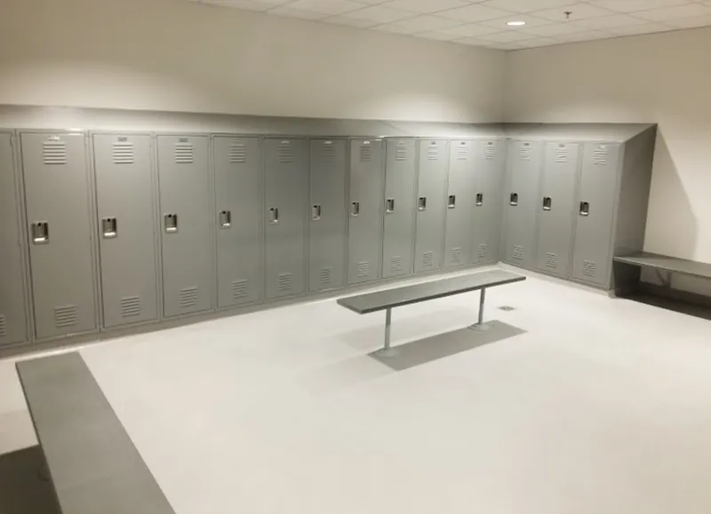 A finished locker room with gray lockers and a central bench