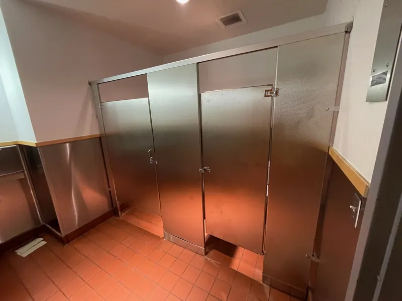 Metal restroom partitions above a terracotta-colored floor