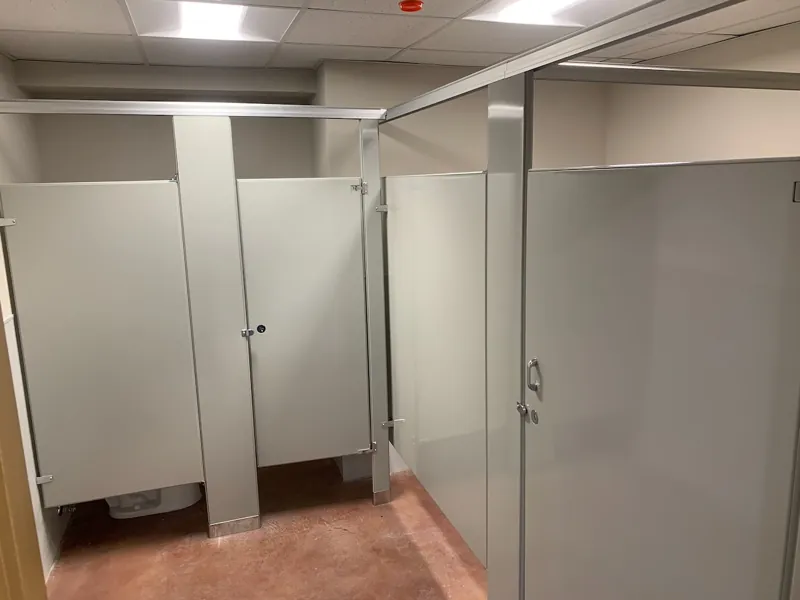 Light gray restroom compartments with overhead bracing