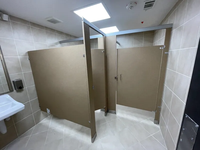 Taupe restroom compartments with white tiled walls