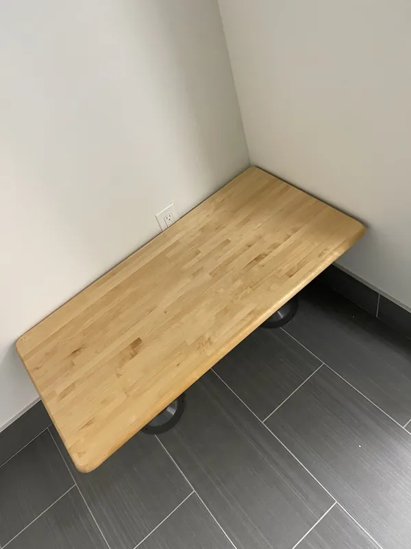 A wood wall-mounted bench above a gray tile floor